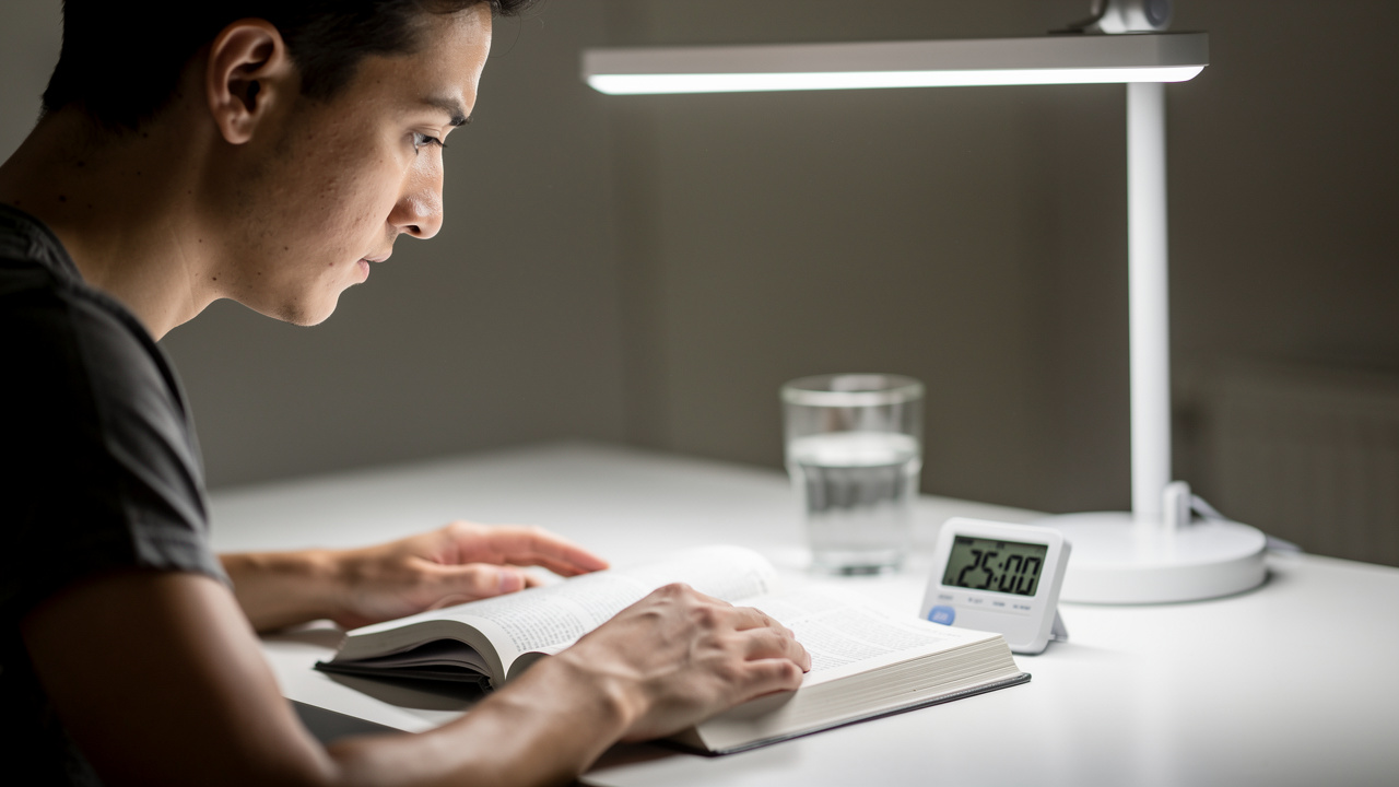 Student studying with visible 25-minute Pomodoro timer on desk.