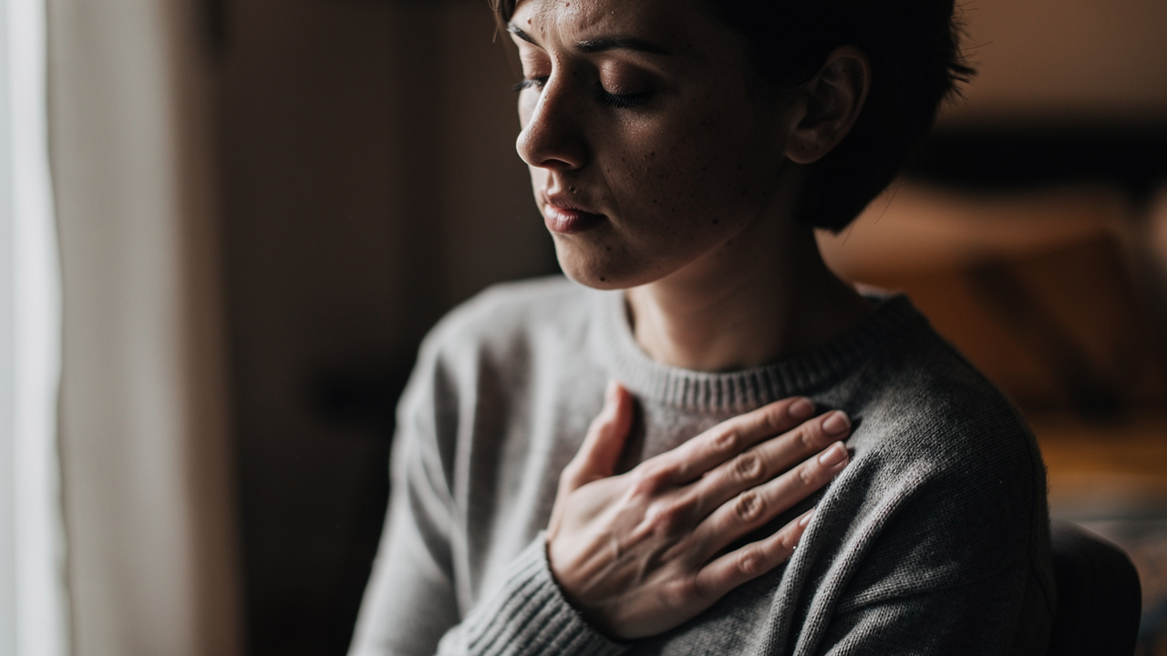 Person pausing in quiet reflection with hand on heart